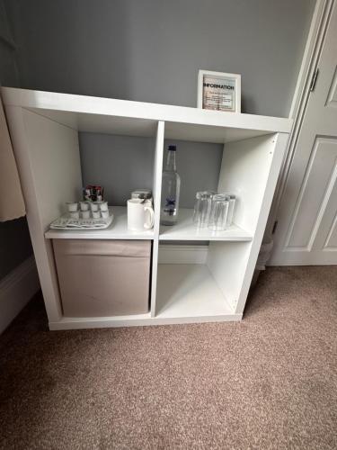 a white book shelf with cups and a bottle at The Six Bells in Rochester