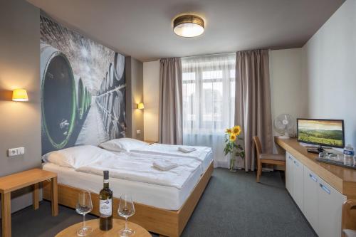 ein Hotelzimmer mit einem Bett und einem Schreibtisch mit Weingläsern in der Unterkunft Hotel Lidový dům in Bzenec