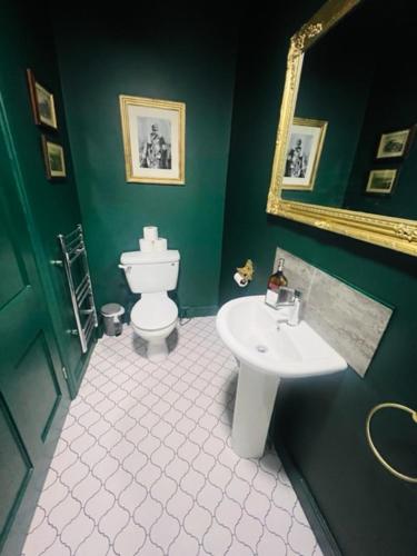 a green bathroom with a toilet and a sink at Mollys Boutique Hotel in Ilkley
