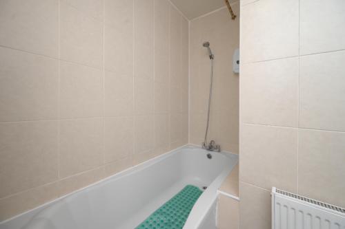 a white bath tub in a bathroom with a green rug at Flexistay Tulsi Aparthotel in Croydon