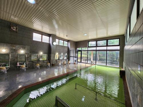 uma grande piscina interior com água verde num edifício em Shugyoku no Yu Yakushido Onsen em Oshu