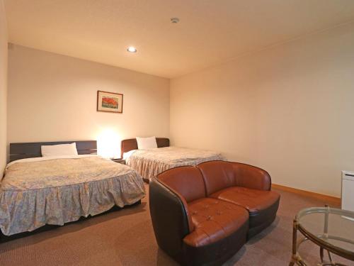 a hotel room with two beds and a chair at Shugyoku no Yu Yakushido Onsen in Oshu