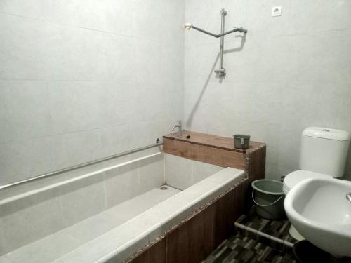 een badkamer met een bad, een toilet en een wastafel bij Pine tree house in Jember