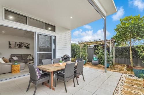 an outdoor patio with a wooden table and chairs at Dog-Friendly Beach House @ Black Rocks by uHoliday in Pottsville