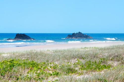 a beach with rocks in the water and grass at Dog-Friendly Beach House @ Black Rocks by uHoliday in Pottsville