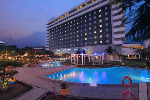 a hotel with a swimming pool in front of a building at ASTON Cirebon Hotel and Convention Center in Cirebon