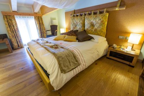 a bedroom with a large bed with a wooden floor at Bio Hotel Brusago Vital & Wellness in Bedollo