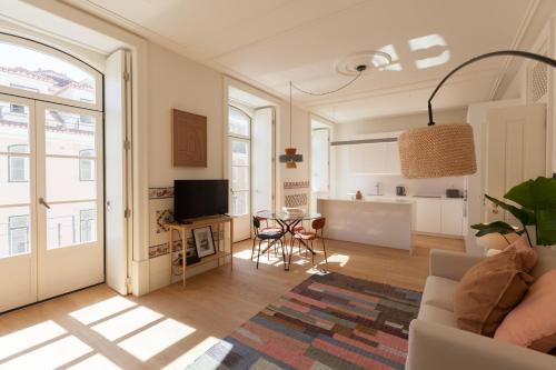 ein Wohnzimmer mit einem Sofa und einem TV sowie eine Küche in der Unterkunft FLH Downtown Central Boho Flat in Lissabon