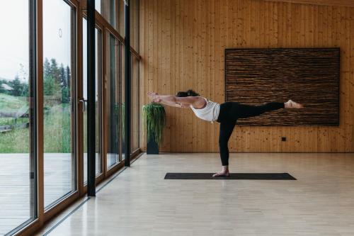 a woman doing a yoga pose in a room with windows at Naturhotel Chesa Valisa in Hirschegg