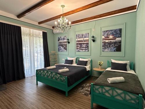a green bedroom with two beds and a chandelier at Pesvebi Design Hotel and Cellar in Borjomi