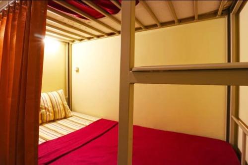 a bedroom with two bunk beds with red sheets at Pondok Backpacker City Square Malang in Bunul
