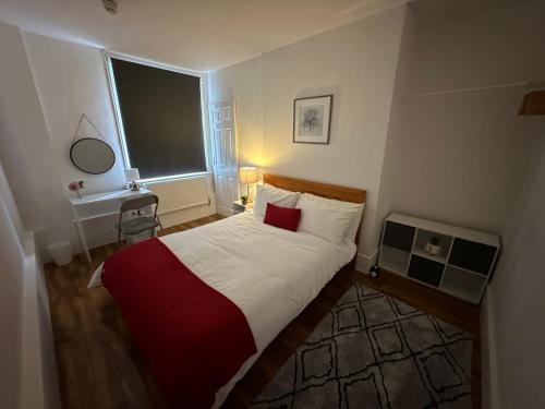 a bedroom with a bed with a red pillow and a window at Cosy Cambridge Centre Flat in Chesterton