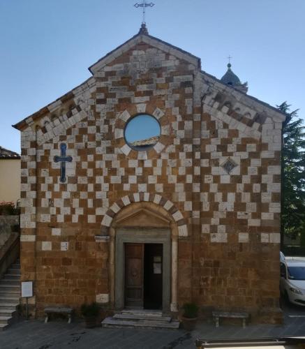 a small brick church with a cross on the front at CasaMoira in Trequanda