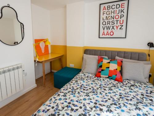 Un dormitorio con una cama con almohadas de colores y un escritorio. en Pass the Keys Modern Stylish apartment with parking, en Bournemouth