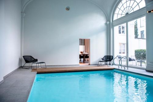 a large swimming pool with two chairs and a table at Pillows Grand Boutique Hotel Reylof Ghent in Ghent