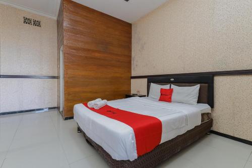 una camera da letto con un grande letto con cuscini rossi di RedDoorz Plus near Museum Angkut Batu 4 a Batu