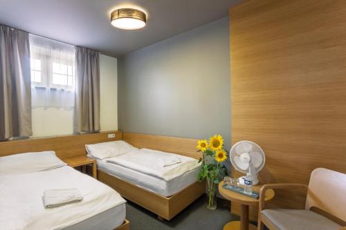 a room with two beds and a table with a vase of flowers at Hotel Lidový dům in Bzenec