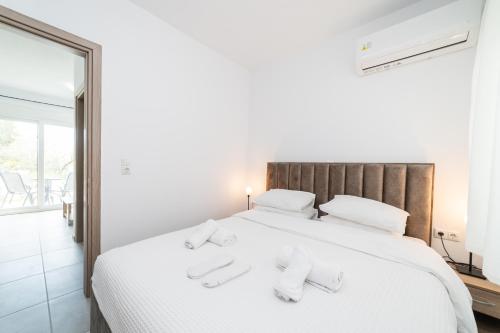 a bedroom with a white bed with two slippers on it at Nefeli & Nefeli Luxury Residential Complexes in Ofrínion
