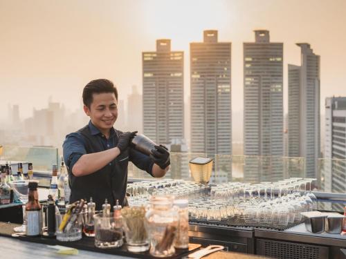 a man is standing behind a table with glasses at SKYVIEW Hotel Bangkok - Sukhumvit in Bangkok