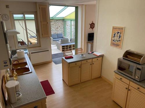 uma sala de estar com uma cozinha e uma sala de estar com um micro-ondas em "La Marinière" - Charmante maison familiale au cœur de la ville em Granville