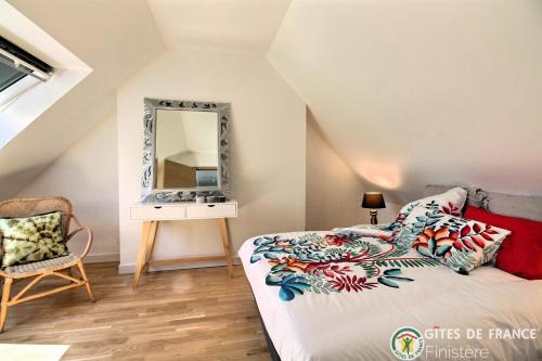 a bedroom with a bed with a mirror and a chair at Le Penty du Petit-Kerauret in Concarneau