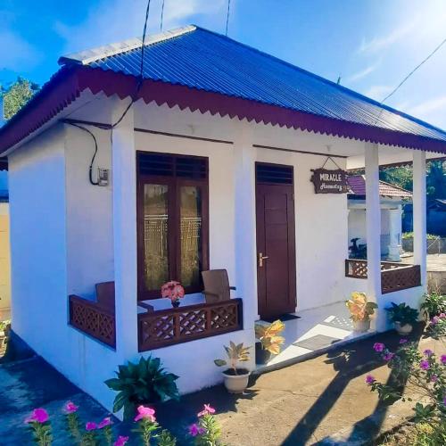 uma pequena casa branca com um telhado azul em Homestay Miracle em Rinondoran
