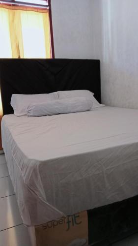 un letto in una camera con lenzuola bianche di Homestay Miracle a Rinondoran