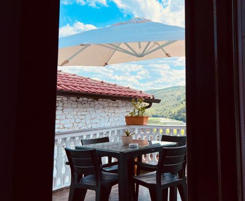 een tafel en stoelen op een balkon met een parasol bij Villa Dona in Berat