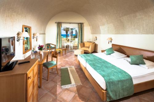 CALIMERA Delfino Beach Resort & Spa في نابل: غرفة نوم بسرير كبير وغرفة معيشة