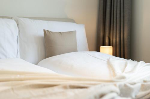 a bed with white sheets and a candle in a bedroom at Central Serviced Apartments in Engelberg