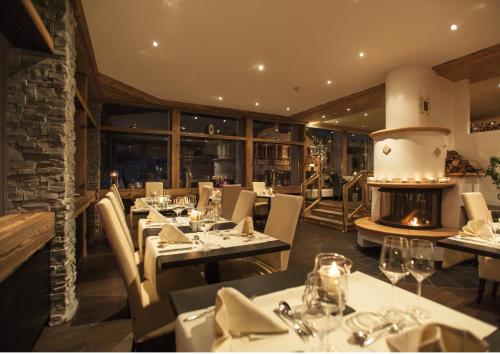 Hotel Quellenhof Leukerbad في لوكرباد: مطعم بطاولات وكراسي ومدفأة