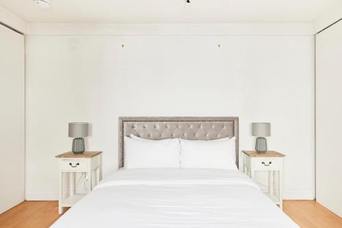 a white bedroom with a white bed with two night stands at The Hampstead Heath Escape - Trendy 1BDR Flat with Balcony in London