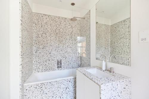 a bathroom with a tub and a sink and a mirror at The Hampstead Heath Escape - Trendy 1BDR Flat with Balcony in London