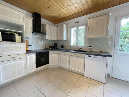 une cuisine avec des armoires blanches et des appareils noirs dans l'établissement Maison indépendante avec terrasse, proche plage et terrain de 1100 m², Noirmoutier-en-l'Île - FR-1-224B-108, à Noirmoutier-en-l'lle