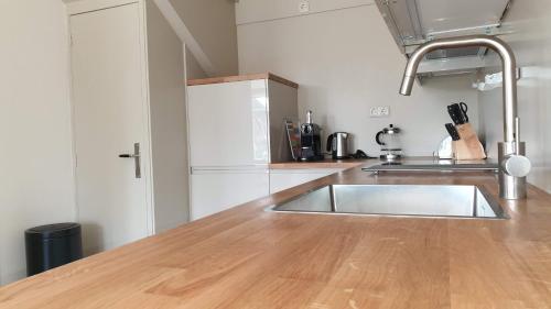 eine Küche mit einer Spüle und einer hölzernen Arbeitsplatte in der Unterkunft It Winkelhûs in Terschelling