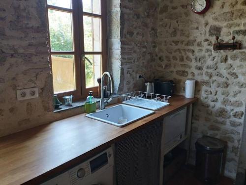 a kitchen counter with a sink and a window at Le Bouchat : Maisonnette au calme pour 2 +1 guest in Cesset