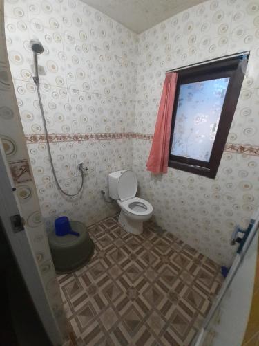 a small bathroom with a toilet and a window at Widodaren Homestay in Probolinggo