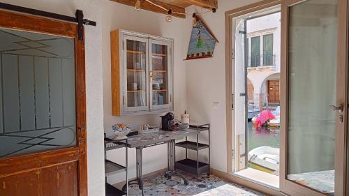 Zimmer mit einem Tisch und einer Glastür mit einem Fenster in der Unterkunft Casa Cuccagna Chioggia - Vista Canal Vena in Chioggia