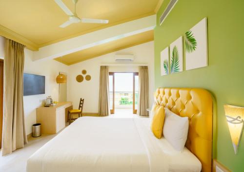 een slaapkamer met een groot bed met een geel hoofdeinde bij Bloom Boutique Baga in Baga