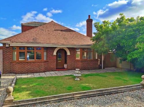 a red brick house with a grass yard in front of it at Leylands 