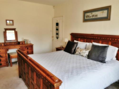 Un dormitorio con una gran cama de madera con almohadas en Leylands, 