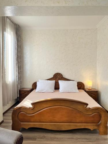 a bedroom with a large wooden bed with two pillows at BATUMI KEY 8 in Batumi