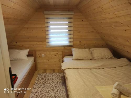 2 łóżka w drewnianym pokoju z oknem w obiekcie BRVNARA MILA w mieście Zaovine