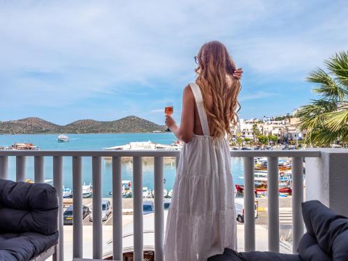a woman standing on a balcony looking at the ocean at Kalypso Suites Hotel - Adults Only in Elounda