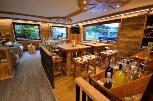a restaurant with wooden tables and chairs and windows at Hotel Cime D'Oro in Madonna di Campiglio