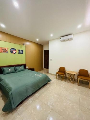 a bedroom with a green bed and two chairs at Bình Minh Motel Pleiku in Pleiku