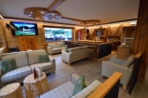 a living room with couches and a flat screen tv at Hotel Cime D'Oro in Madonna di Campiglio