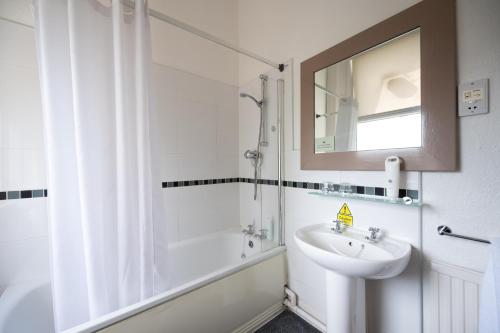 Baño blanco con lavabo y espejo en Channings Hotel by Greene King Inns en Bristol