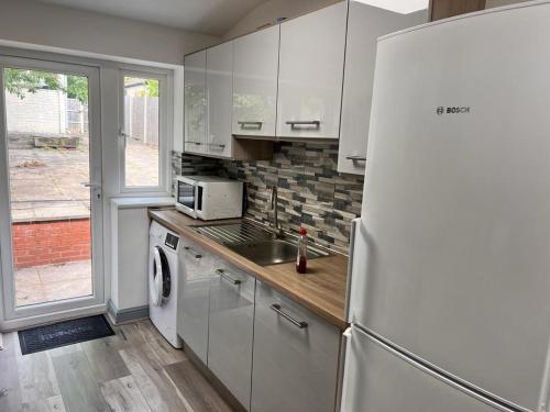 a kitchen with a sink and a refrigerator at Ensuite Room Selly Oak - Milner Road in Birmingham