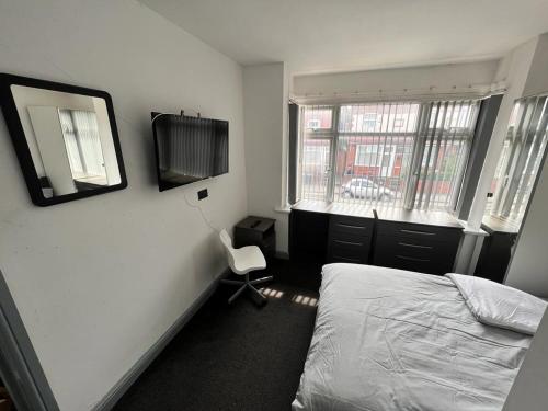 a bedroom with a bed and a mirror and a chair at Ensuite Room Selly Oak - Milner Road in Birmingham